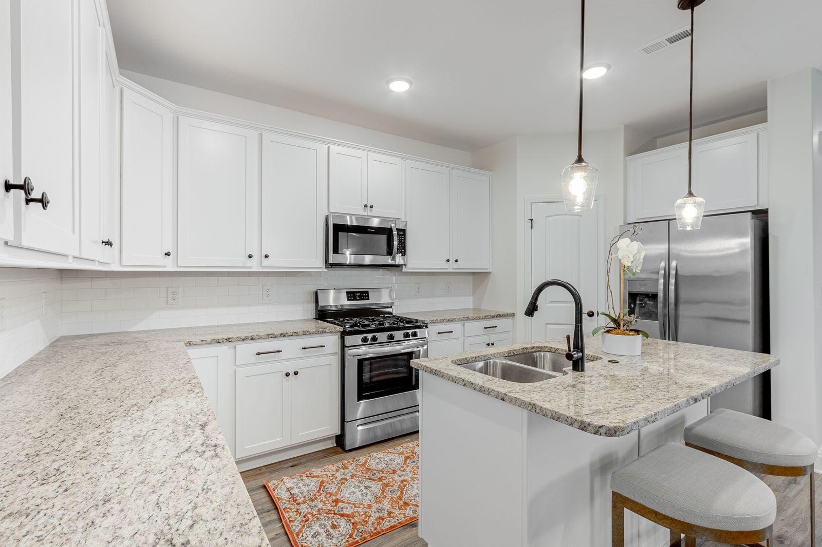 Preston Park modern kitchen with island, white cabinets, pendant lights, and premium finishes
